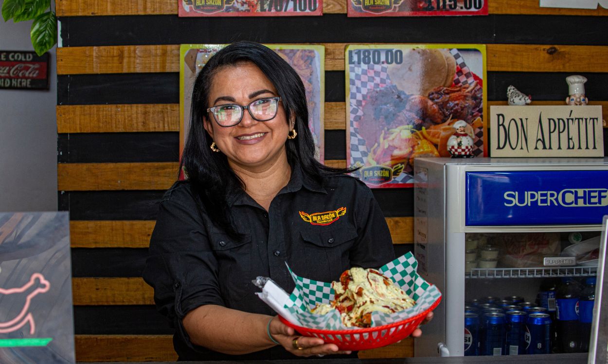 Emprendedora con una cálida sonrisa presentando su deliciosa oferta gastronómica, preparada con dedicación y pasión